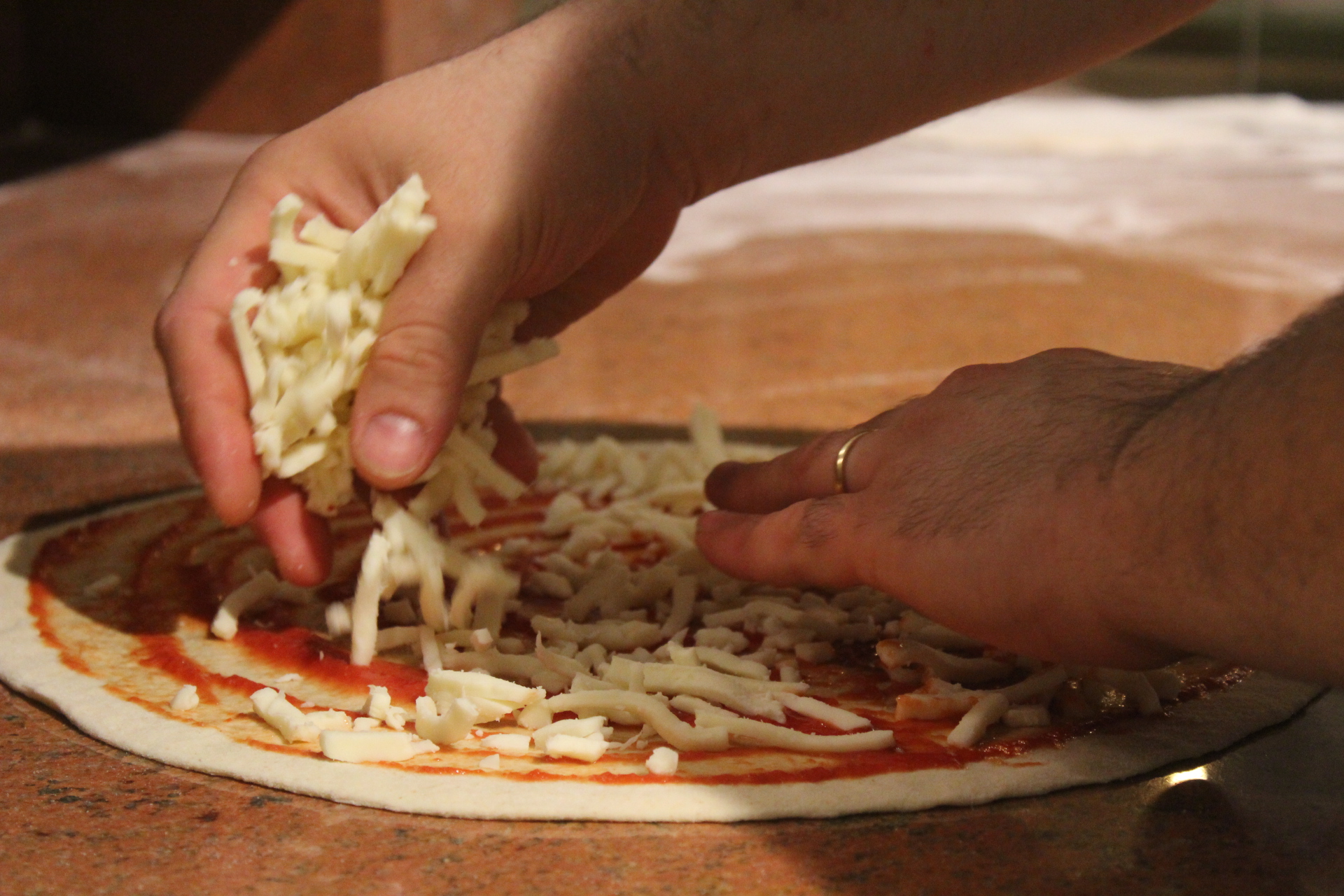 Filippo, il pizzaiolo, mentre farcisce l'impasto con pomodoro e mozzarella